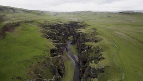 Fjaðrárgljúfur-canyon-in-iceland-with-lush-green-landscape-and-winding-river,-aerial-view