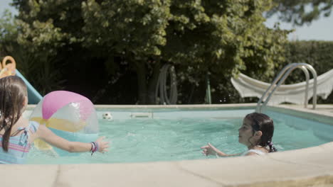 Happy-children-playing-ball-game-in-swimming-pool-on-sunny-day.