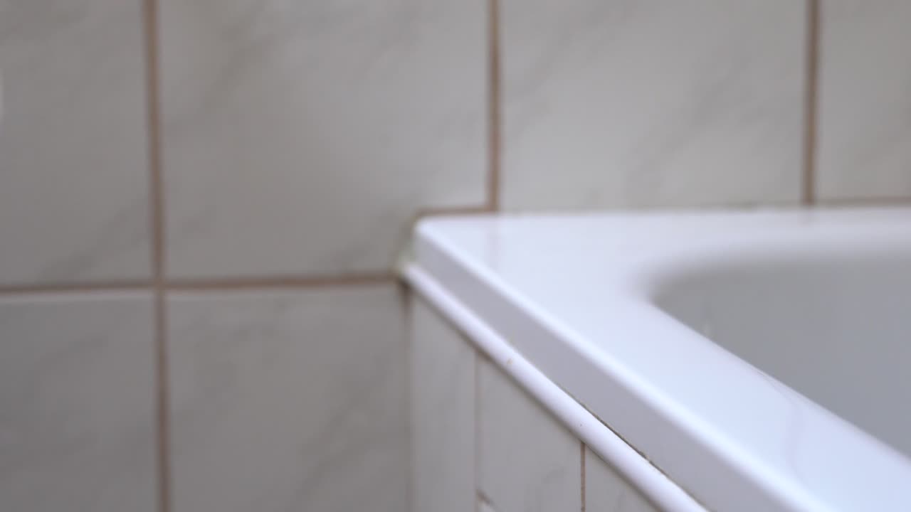 mano extendiéndose y recogiendo un rollo de papel higiénico en el baño