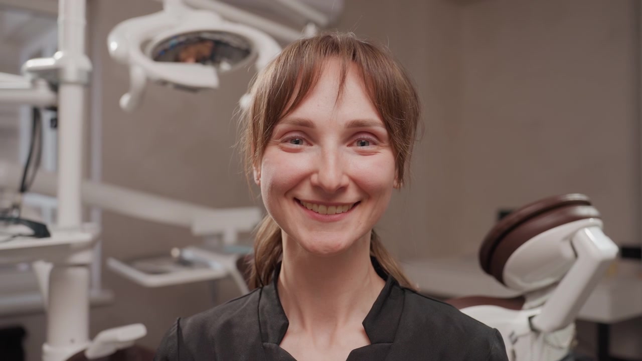 Närbild på tandhygienist som bär skyddsglasögon på en tandregleringsklinik och justerar ansiktsskydd. Den professionella ses med medicinsk utrustning och förbereder sig för patientvård.