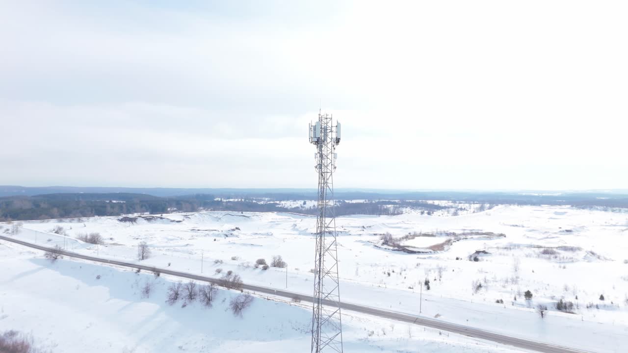 A highangle drone shot of a cellular telecommunication tower standing in a vast snowcovered rural landscape. Ideal for technology, infrastructure, and connectivity concepts