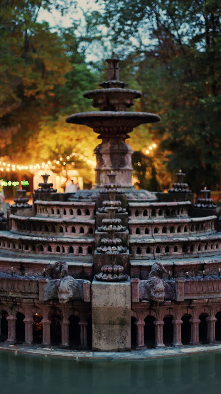 Close up of a water fountain in the Stephen the Great Central Park in Chisinau, Moldova with golden lights in the background. Vertical