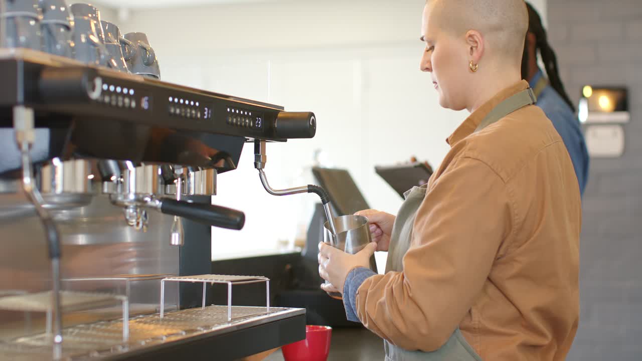 Collega che usa un tablet. Barista bianca che prepara la schiuma del latte e la versa nella tazza in un bar, spazio per il testo