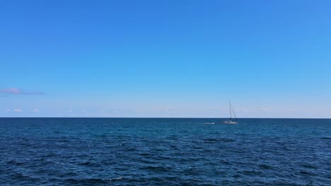 a serene sailboat navigates the crystal-clear waters off cala varques, showcasing the beauty of porto cristo. the bright blue sky enhances the peaceful atmosphere.