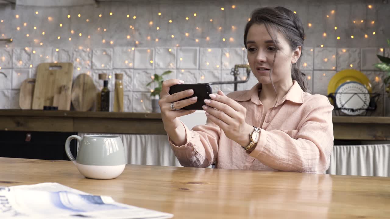 Donna che utilizza lo smartphone in cucina