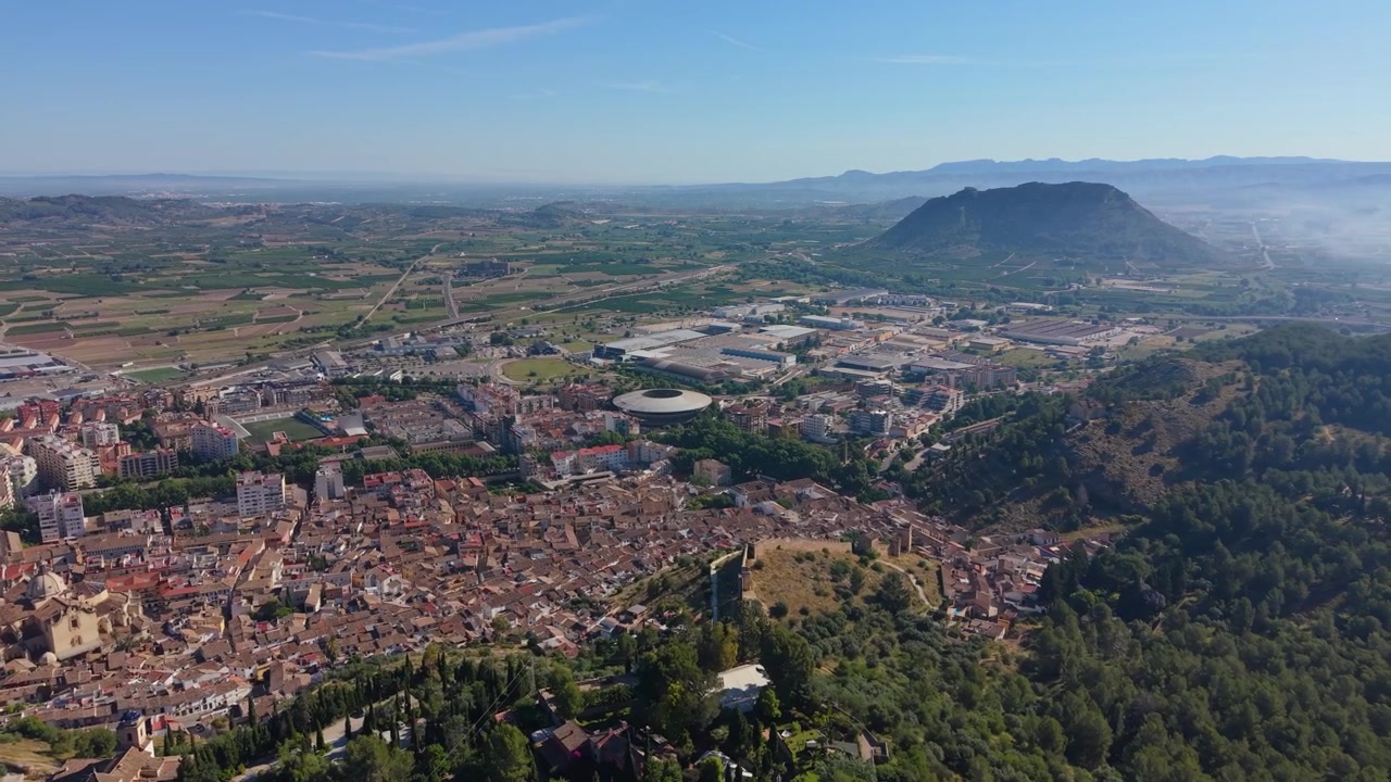 Ampia veduta aerea con drone di Xàtiva, Spagna, che mostra il centro storico, la campagna circostante, il distretto industriale e i suggestivi paesaggi montani