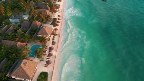 Coastal-resort-with-thatched-roofs-along-a-pristine-beachfront