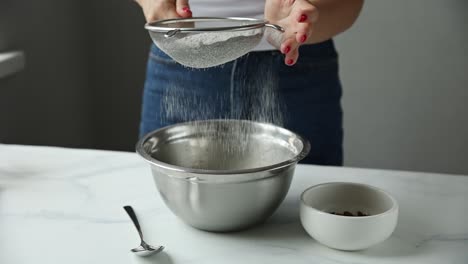 woman sifting flour into a mixing bowl