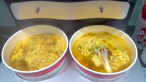 dos cuencos de fideos instantáneos hirviendo con agua caliente añadida