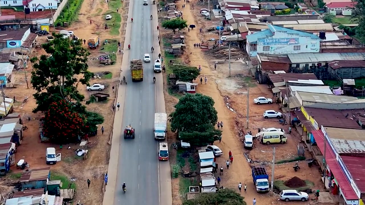 Mercato di un villaggio rurale in Kenya, povertà in Africa, infrastrutture stradali scadenti, auto che si muovono su strade mal tenute in Kenya