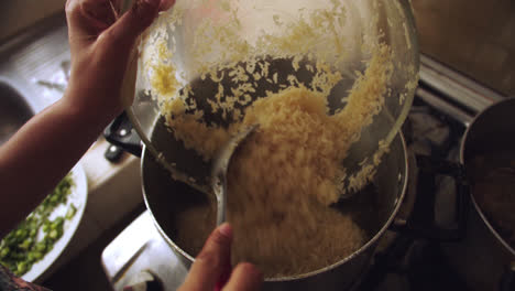 pouring raw rice with ladle into a pot to be cooked