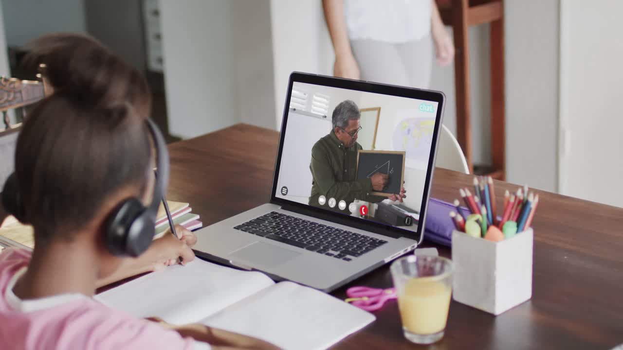 una estudiante diversa teniendo clase en una llamada de video portátil con un maestro en cámara lenta