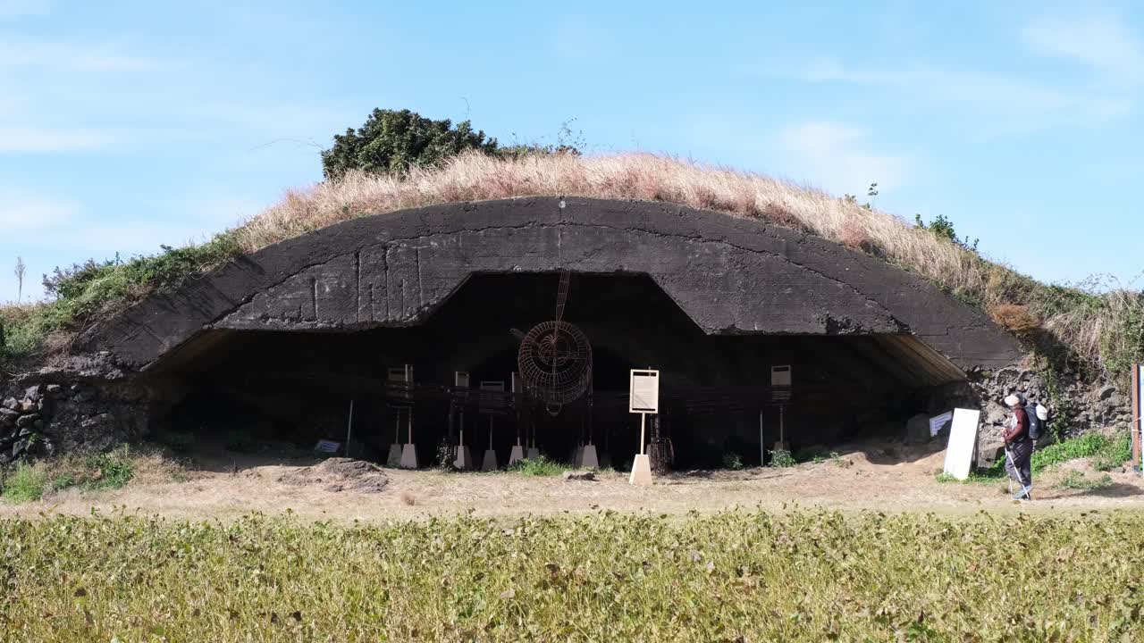 Vista dettagliata di un bunker militare della Seconda Guerra Mondiale sull'isola di Jeju, Corea del Sud. Cattura l'architettura storica, immerso in una campagna lussureggiante sotto cieli sereni. Perfetto per filmati di viaggio e storia.