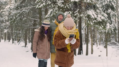 Mädchen,-Das-Fotos-Mit-Smartphone-In-Winterkleidung-Im-Verschneiten-Wald-Macht