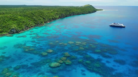 drone volando hacia atrás sobre el arrecife de coral en fiji con un crucero anclado frente a la costa