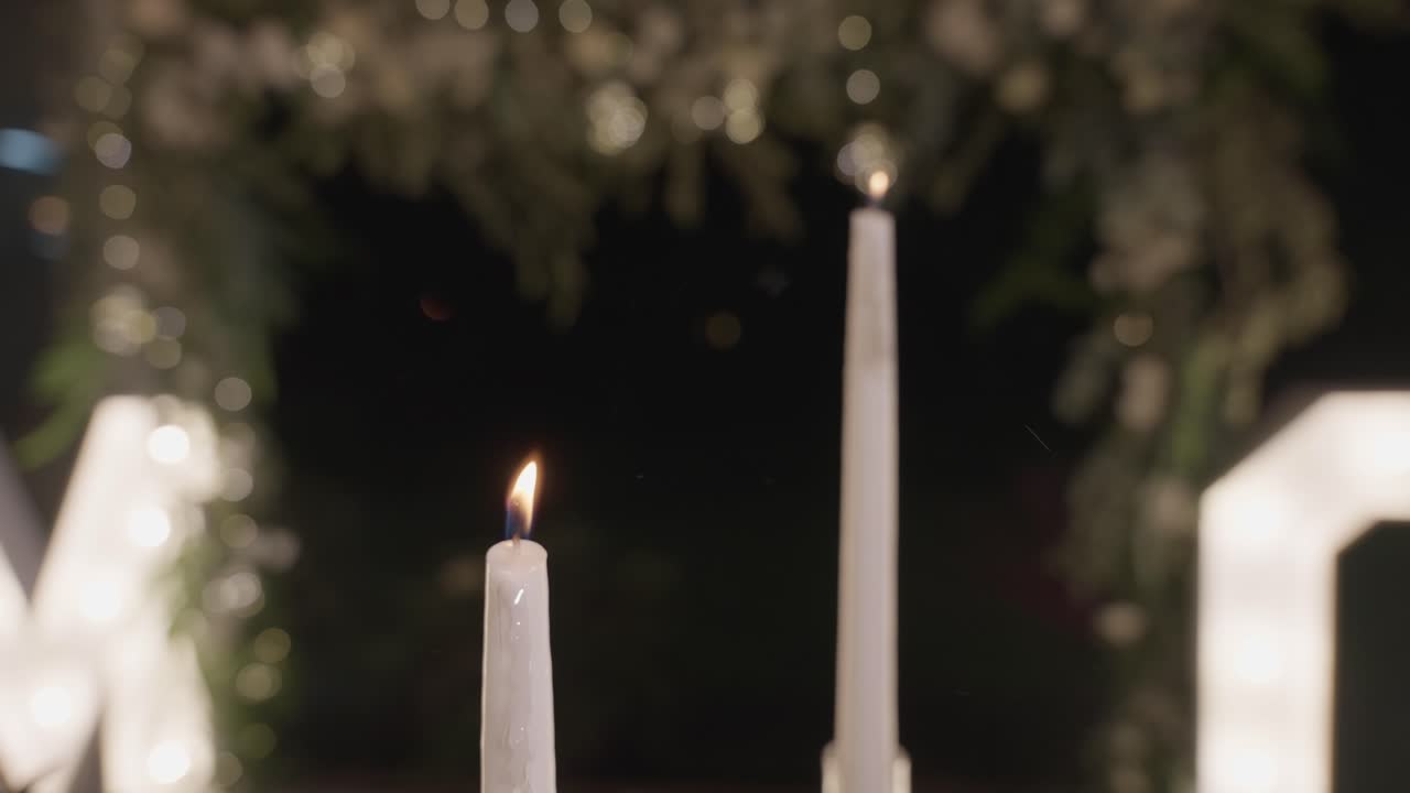 Due candele bianche accese con fumo visibile, in interni.
