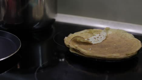 the process of cooking homemade pancakes. woman puts pancake from pan to plate