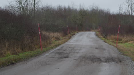 Empty-rural-dirt-road,-in-autumn-Sweden,-pan-and-tilt-on-a-rainy-day