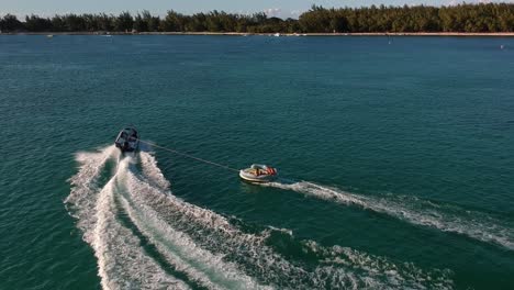 aerial shot of a sportboat pulling a big float with people in it