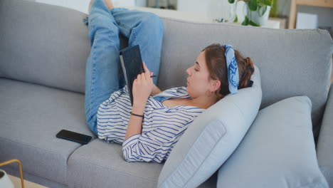 Nachdenkliche-Frau-Beschäftigt-Sich-Mit-Digitalem-Tablet-Auf-Dem-Sofa