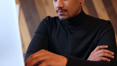 Guy-crossing-his-arms-while-waiting-in-front-of-his-laptop,-dynamic-tilting-upward