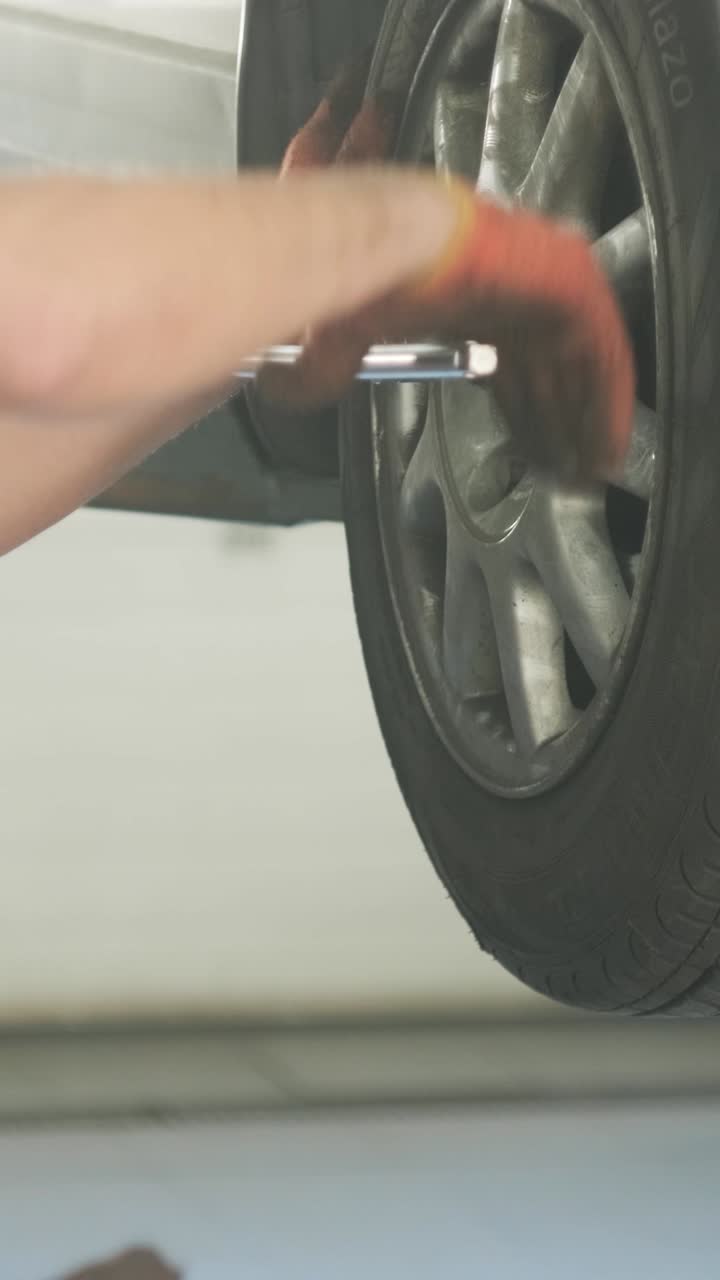 Auto Mechanic Tightening Car Wheel Lug Nuts in Service Shop