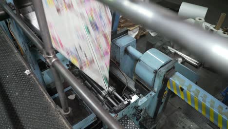 bending newspaper sheets on machine. printing house. new newspapers are printed in multicolored colors on paper sheets. media, article, headline, daily news, print edition, journalism, politics