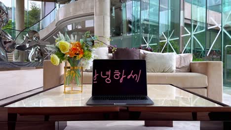 맥북이 한국어로 "안하세요"를 표시하고 있습니다. 테이프로 인 창문이 있는 고급스러운 저택의 테이블 위에