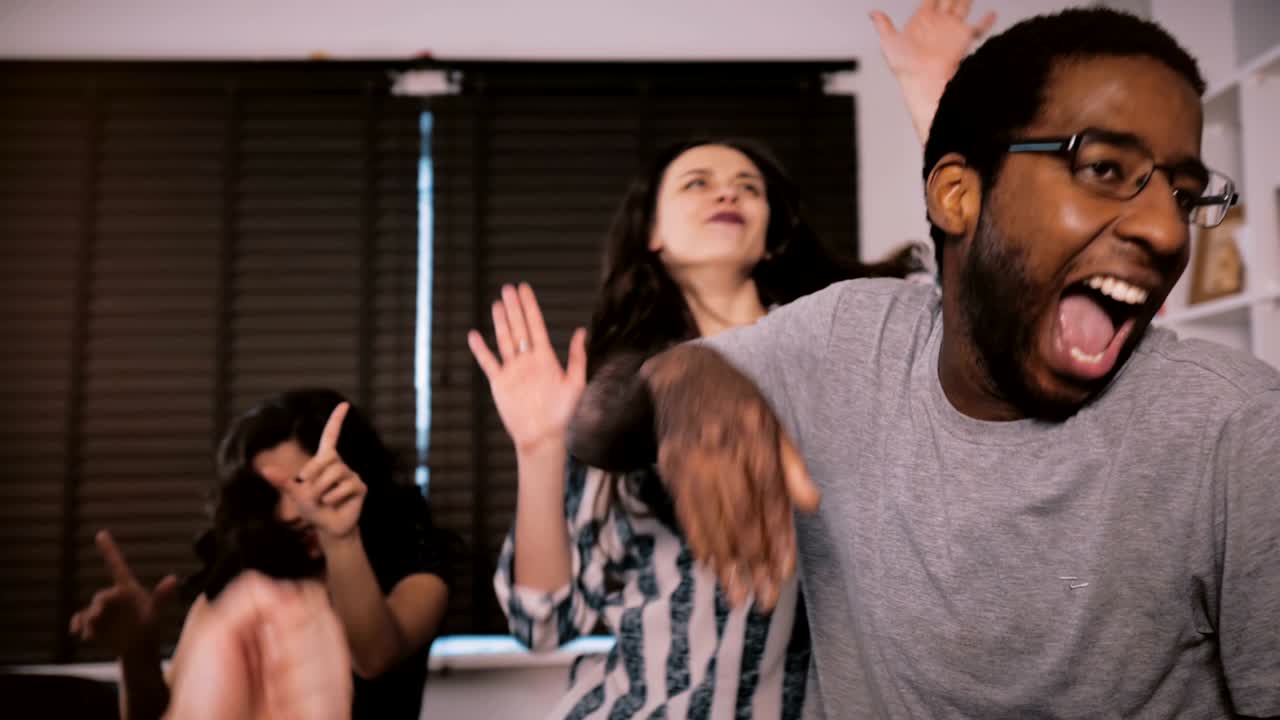 jóvenes multiétnicos emocionados bailan juntos, celebrando la amistad y la vida en una divertida fiesta casera en cámara lenta