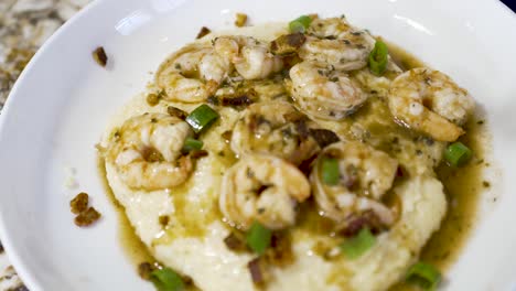 sprinkling chopped green onions on a plate of shrimp and grits - dynamic motion