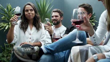jóvenes riendo bebiendo vino tinto en la terraza
