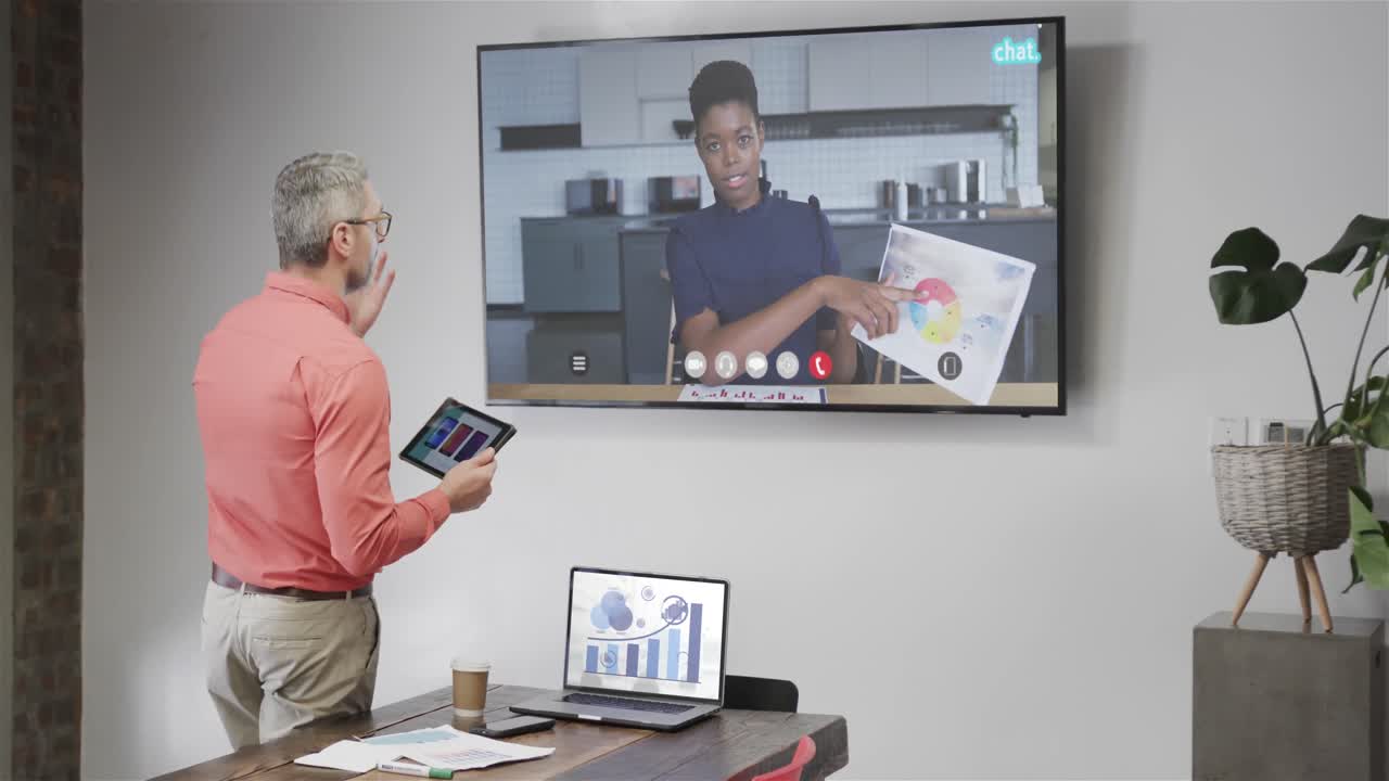Caucasian businessman on video call with african american female colleague on tv screen