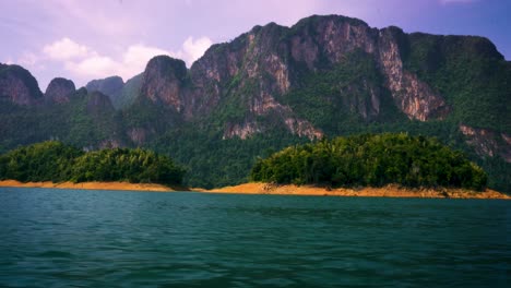 navegando por pequeñas islas en el lago cheow lan con vistas a los acantilados de piedra caliza en el parque nacional khao sok, tailandia
