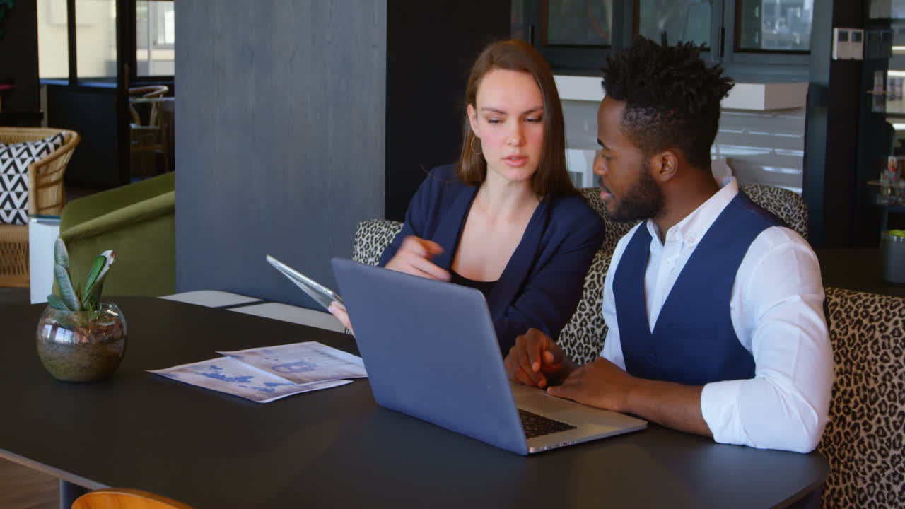 Front view of young cool mixed-race business team planning and sitting at table of modern office 4k