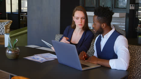 Front-view-of-young-cool-mixed-race-business-team-planning-and-sitting-at-table-of-modern-office-4k