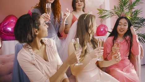 Side-View-Of-Group-Of-Friends-And-Bachelor-Girl-Holding-Champagne-Crystal-Glasses-While-Dancing-Sitting-On-Sofa