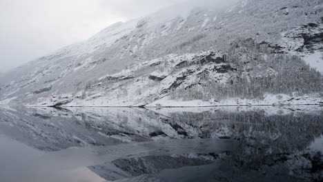 pov footage of a boat ride through geirangerfjord, norway, highlighting the fjord's tranquil beauty and the surrounding snowy mountains in winter