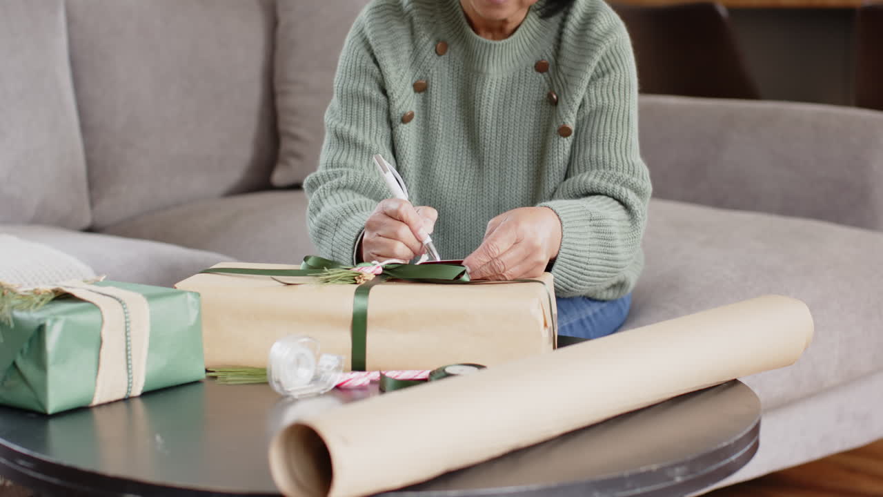 Elderly woman wrapping Christmas gifts at home, focusing on festive details