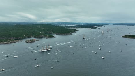 numerous sailboats and small vessels traverse the waters of a picturesque archipelago under a cloudy sky. the lush green hillsides frame the serene seascape, showcasing nature's beauty