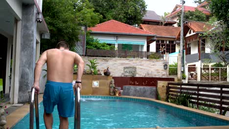 the man descends into the pool and swims