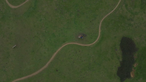 mountain biker sitting on bench in green field next to trail, descending drone