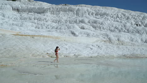 mujer en bikini caminando en la terraza de travertino y piscina en pamukkale, turquía