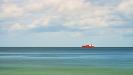 Cloudscape-Timelapse-Over-Baltic-Sea-With-One-Large,-Red-and-White-Tanker-Ship-Floating-In-Far-Distance-on-Horizon-In-Calm-Waters