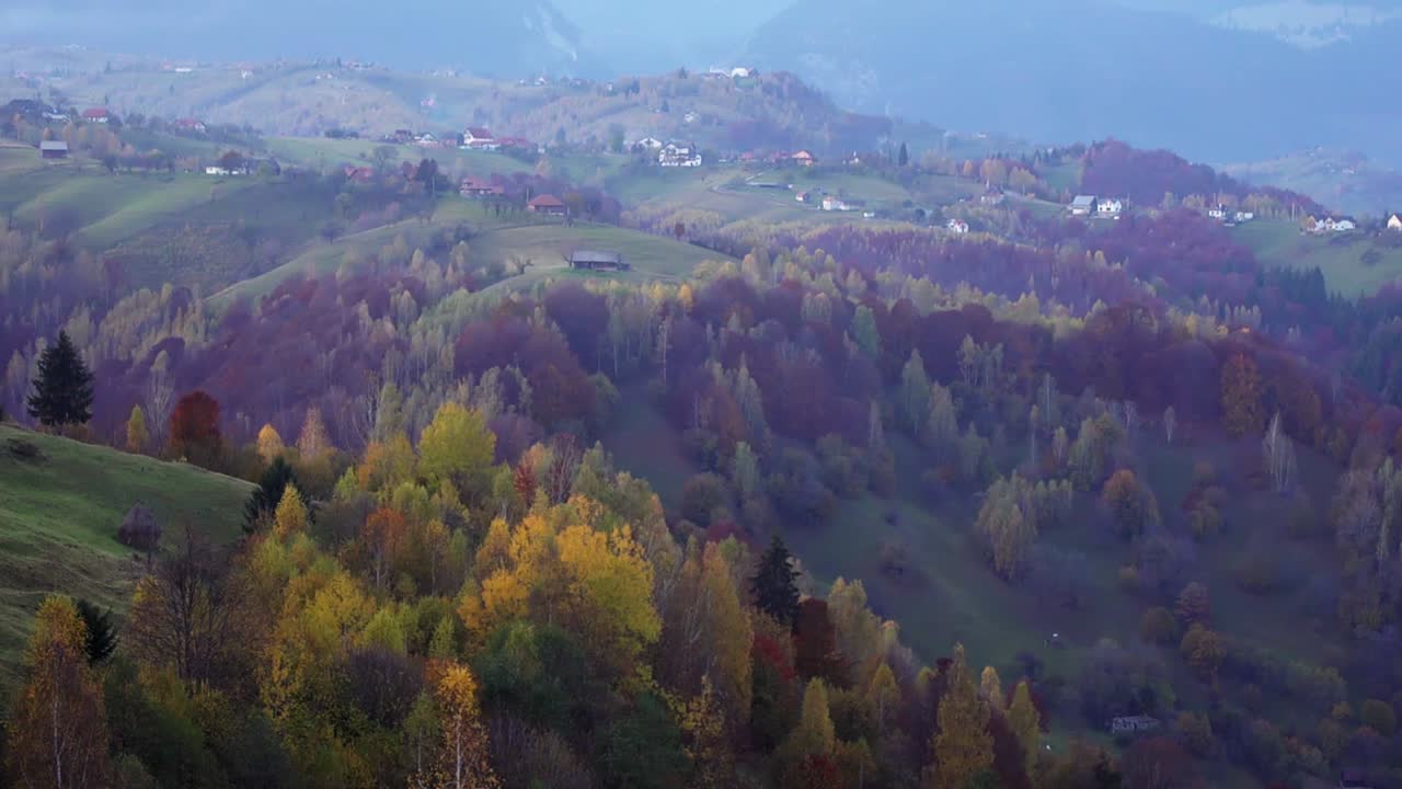 hermoso bosque de montaña otoñal con un tranquilo pueblo en piatra craiului, condado de brasov, rumania en una mañana brumosa, panorámica hacia la izquierda