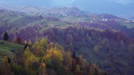 Hermoso-Bosque-De-Montaña-De-Otoño-Con-Un-Pueblo-Tranquilo-En-Piatra-Craiului,-Condado-De-Brasov,-Rumania-En-Una-Mañana-Brumosa,-Panorámica-A-La-Izquierda