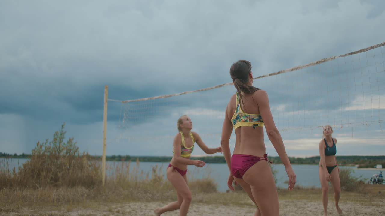 젊은 운동선수들이 모래 코트에서 훈련하고 여름 휴가 동안 해변 배구 경기를 하고 있습니다.