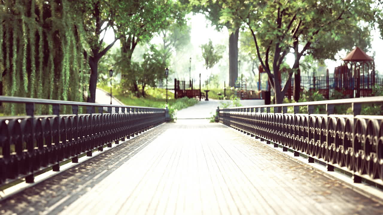 울창 한 초록색 과 놀이터 를 가진 아름다운 공원 으로 이어지는 경치 좋은 다리