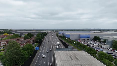 drone rising over m25 motorway, cloudy sky, as cars enter tunnel, london, uk
