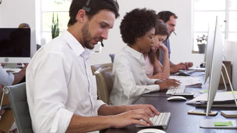 colleagues with headsets on working at computers in office