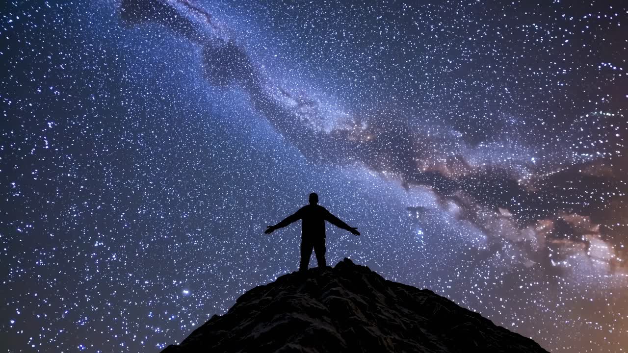 Silueta de una persona en la cima de una colina, con los brazos extendidos, bajo un cielo estrellado